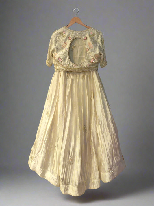 Vintage dress with floral embroidery on a hanger against a reflective surface