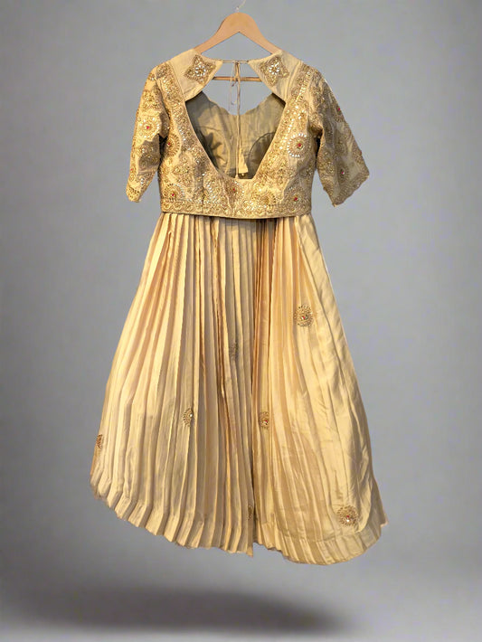 Beige dress with gold embroidery on a hanger against a dark background