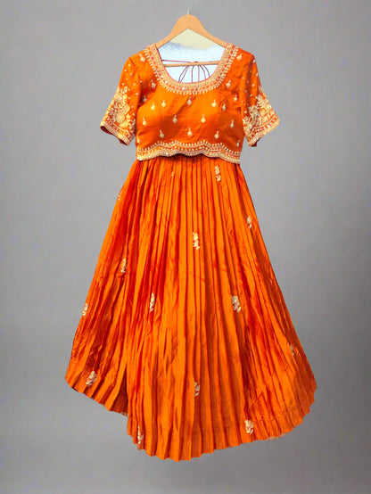 Orange traditional outfit with intricate patterns on a hanger against a neutral background