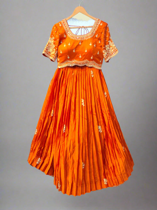 Orange traditional outfit with intricate patterns on a hanger against a neutral background