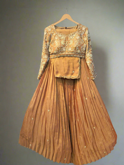 Brown traditional outfit with gold embroidery on a hanger against a metallic background