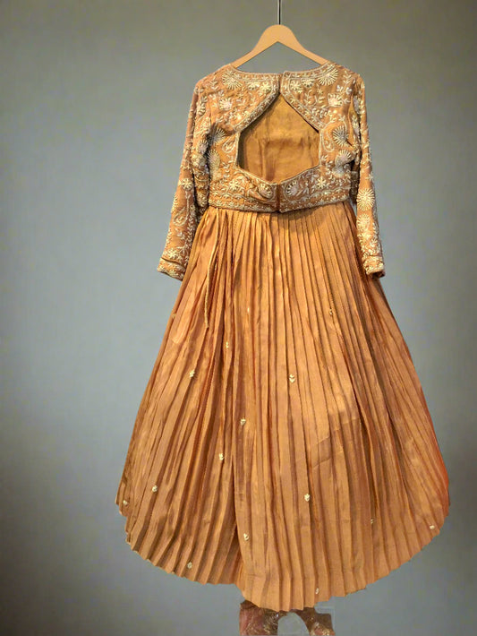 Brown traditional outfit with gold embroidery on a hanger against a reflective surface.