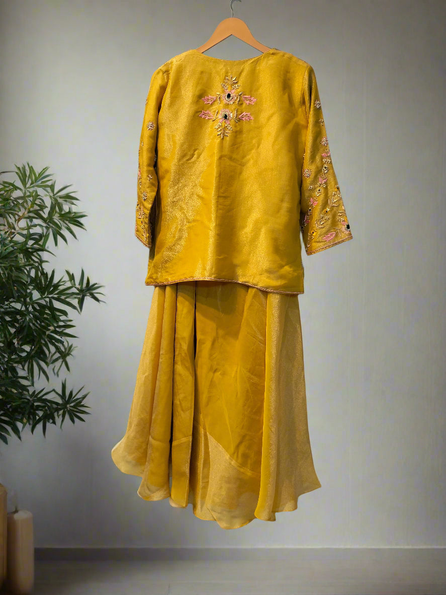 Yellow embroidered outfit on a hanger against a reflective surface