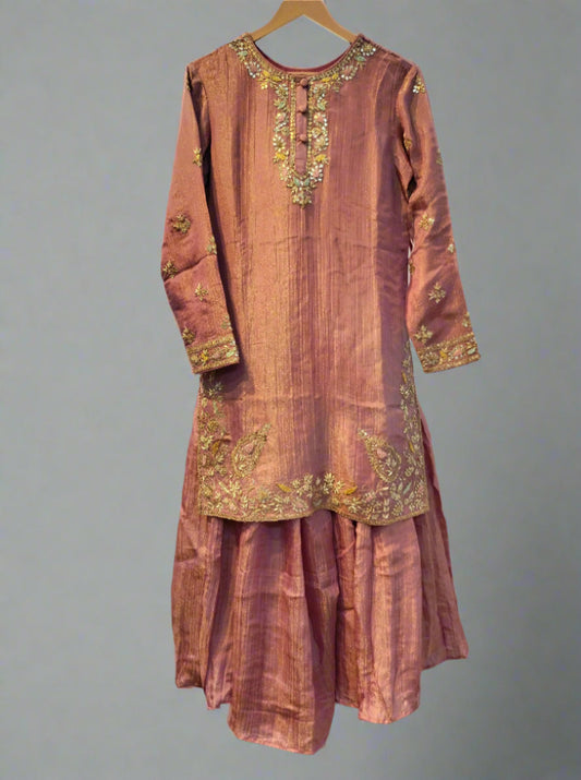 Pink traditional outfit with gold embroidery on a hanger against a neutral background